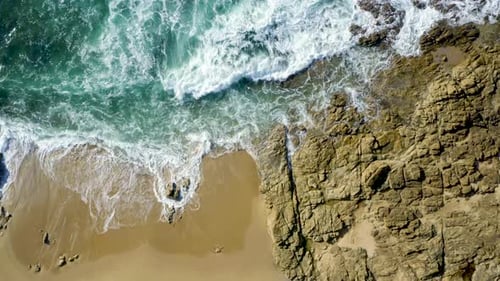 Aerial top view of waves break on rocks. Aerial drone top down view bird eye view of sea blue waves