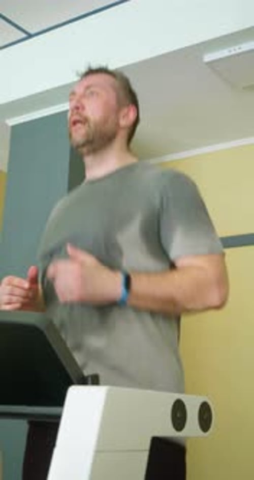 Vertical Footage of a Middleaged Man During Treadmill Workout in a Gym