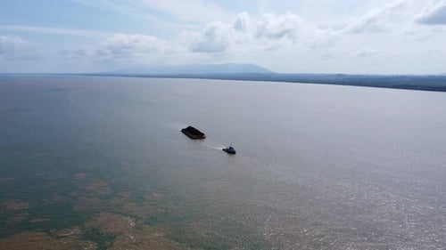 A ship towing a barge carrying a cargo of coal for shipping