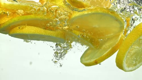 Slices of Lemon Dropping in Water with Bubbles