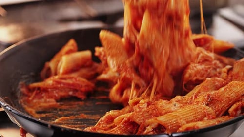 Chef Cooking Penne Pasta with Tomato Sauce and Mozalerra Cheese in Pan Close Up