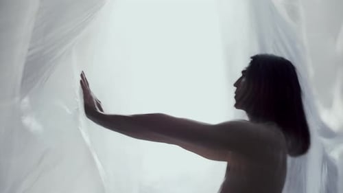 Shirtless Dancer Performing Expressive Dance between Layers of Plastic Wrap