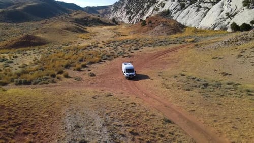 Pull away of a van driving out of an arid space and rocky cliffs