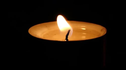 Single Candle Flame Flickering in the Darkness