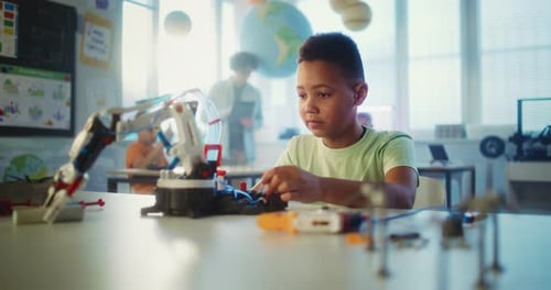 Intelligenter Junge der Grundschule studiert während des naturwissenschaftlichen Unterrichts ein Roboterarmmodell