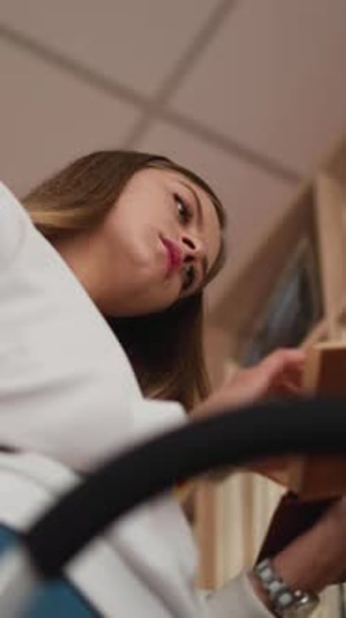 Young Woman Chooses Book From Shelf in Bookstore