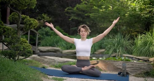 Young Caucasian Woman in Sportswear Sits on Yoga Mat Outdoor and Meditating