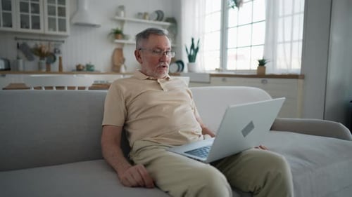 Mature Man Using Laptop On Couch Indoors