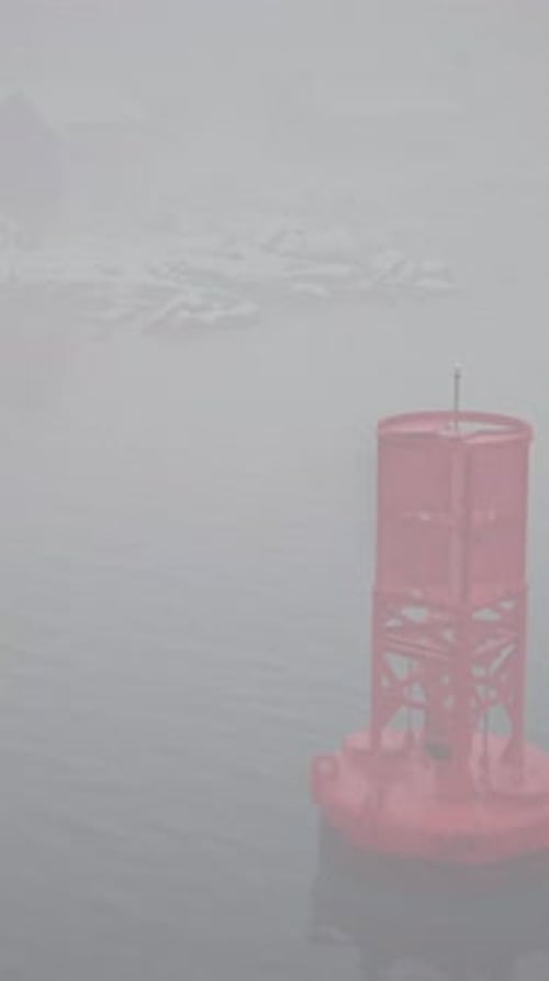 Red Metal Buoy Floating in Norwegian Sea on Foggy Day