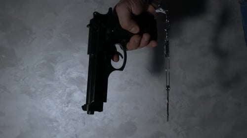 Hand Holding a Gun in Handcuffs Close Up