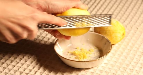 Zesting Fresh Lemon with Grater in Kitchen