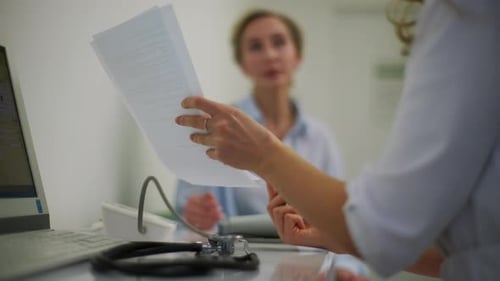 Doctor Reviews Documents with Patient in Clinic
