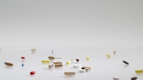 Verschiedene bunte Medizinpillen, die auf einen weißen Hintergrund fallen