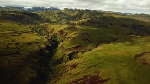 Aerial panoramic landscape view of a river flowing in a mountain canyon, in Iceland