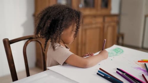 Young Child Drawing with Pencils at Table