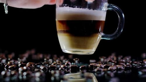 Closeup Table with Scattered Coffee Beans and Female Hand Placing Cup with Beverage Leaving in Slow