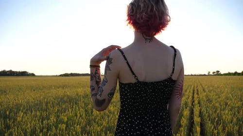 Pretty Young Punk Girl Taking Off Black Strap of Dress From Shoulder at Green Barley Field Beautiful