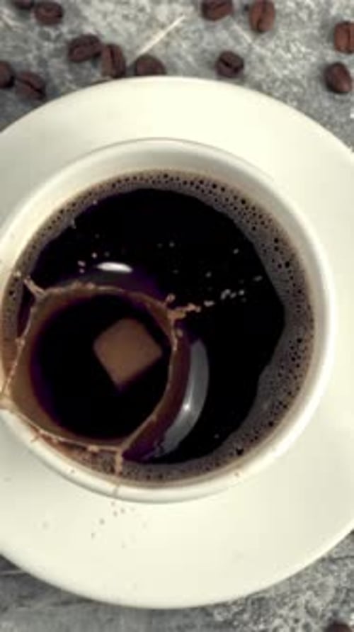 Super Slow Motion in a Cup of Coffee Drops a Piece of Sugar with Splashes Filmed on a Highspeed