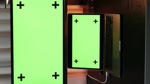 Big computer and laptop screens with green chroma key. Vertical video