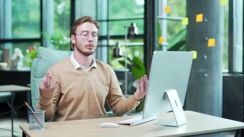 Young Man Meditating at Desk in Sunny Office