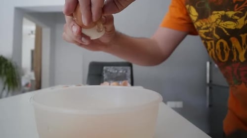 Male Hands Cracking Open A Brown Egg Into A Bowl On The Kitchen Counter Slow Motion
