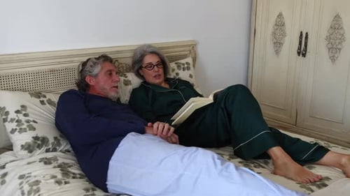 Mature Couple Reading and Talking in Bed Together