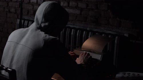 Hooded Figure Types on Classic Typewriter in the Dark