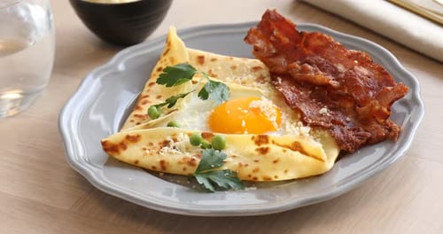 Delicious crepe with egg, bacon and parmesan cheese on wooden table, closeup