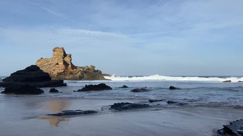 a Waves roll over dark volcanic rock as the tide breathes in and out, creating a calm, raw coastal