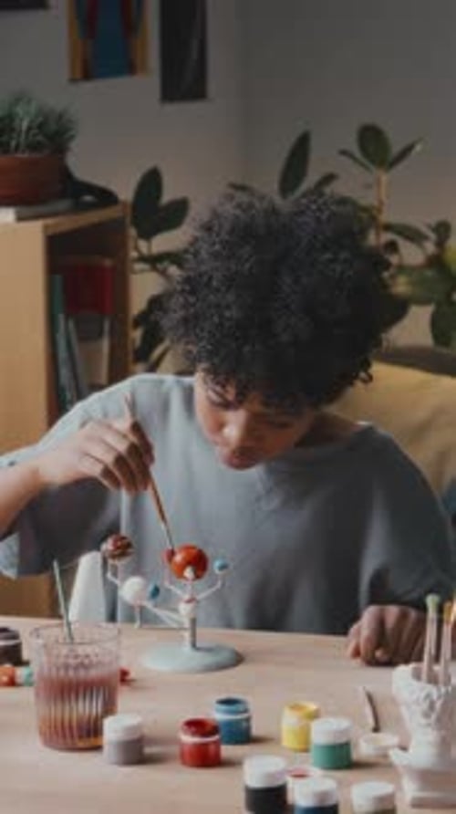 Little Boy Using Paint and Coloring Solar System Model at Home