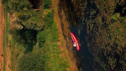 Aerial drone view following kayak paddling in river at sunset