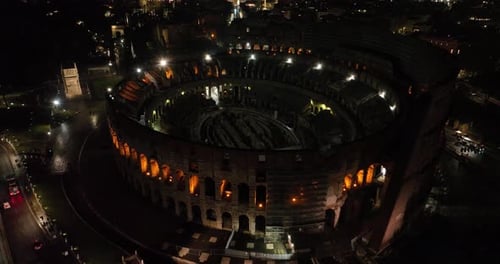 Aerial fly drone view of Colosseum or Coliseum at night, Rome, Italy, Europe. Ancient Roman ruin is