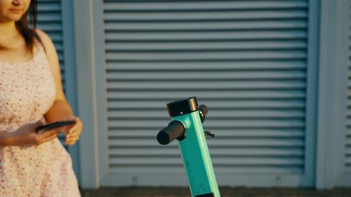 Woman Rents Electric Scooter Using Mobile Phone App at the Street