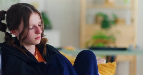 Sad Teenage Girl Puts Her Mobile Phone on the Sofa