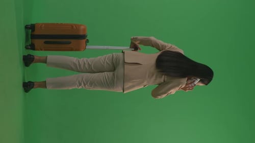 Businesswoman With Luggage Talking On Smartphone While Walking And Standing In The Green Screen