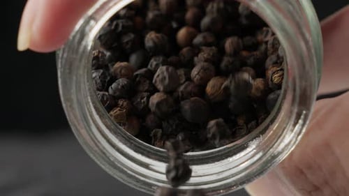 Person Pouring Dried Whole Black Peppercorns. - close up shot