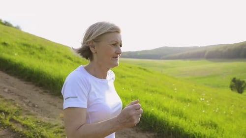 Beautiful Senior Woman Running Outside on Green Hills