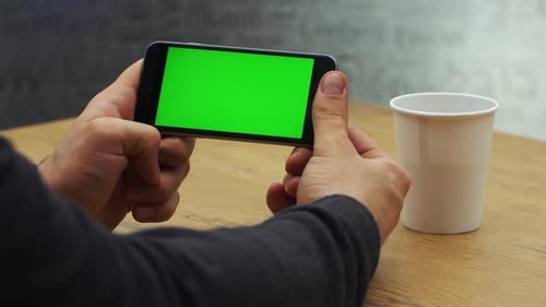 Man Using Horizontal Smartphone with Green Screen Closeup Shot of Man's Hands with Mobile Phone