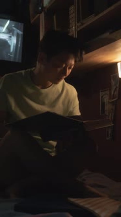 Asian Woman Studying Textbook at Night in Tiny Flat