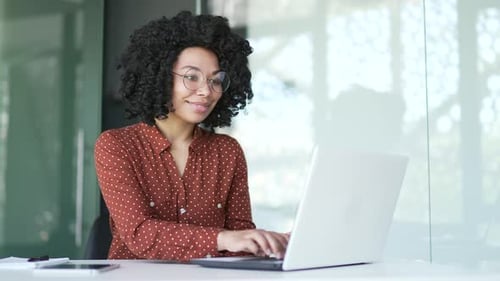 Young african american female employee typing on laptop sitting at workplace in business office.