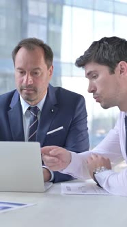 Businessmen Working Together on Laptop in Modern Office