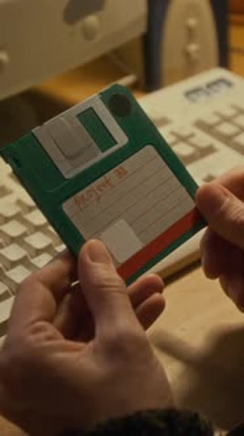 Vertical of Female Hands Holding Vintage Floppy Disk with Work Project