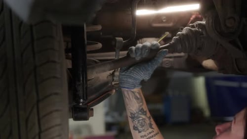 Close Up Hand Mechanic in Car Service Checks Suspension of Car That is Raised on Lift in Repair Zone