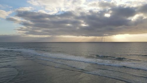 4K Static Drone Shot Of Sun Behind Clouds Illuminating Waves