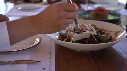 Person Eating Salad with Wine at Restaurant
