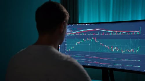 View From Shoulder of Concentrated Crypto Trader Sitting in Front of Computers Making Professional
