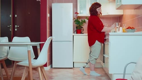 Copy Space Shot Beautiful Happy Woman with Bionic Cyber Prosthetic Leg Walks in Light Kitchen to