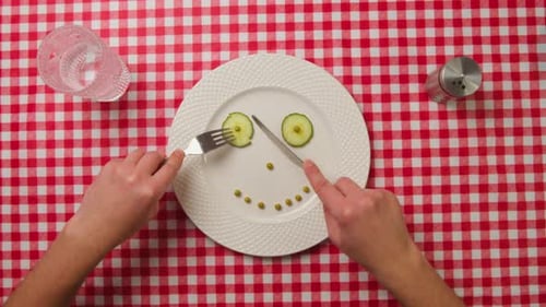 Vegetables in a Plate Top Down View and Male Hands with a Fork and Knife