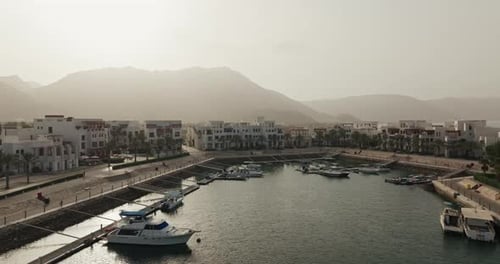 Drohnenaufnahme von Wohngebäuden und dem Jachthafen in Sifah, Oman
