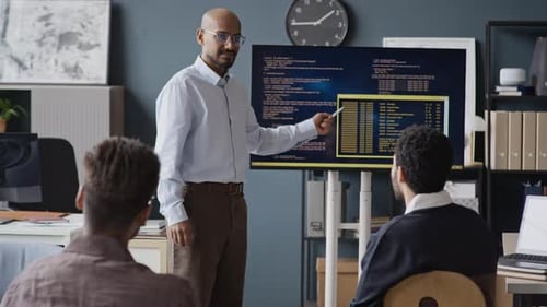 Indischer männlicher Programmierer präsentiert dem Team im Büro Code auf dem Bildschirm